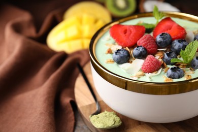 Tasty matcha smoothie bowl served with berries and oatmeal on table, closeup with space for text. Healthy breakfast