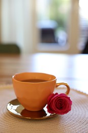 Photo of Cup of hot drink and red rose on table indoors. Space for text