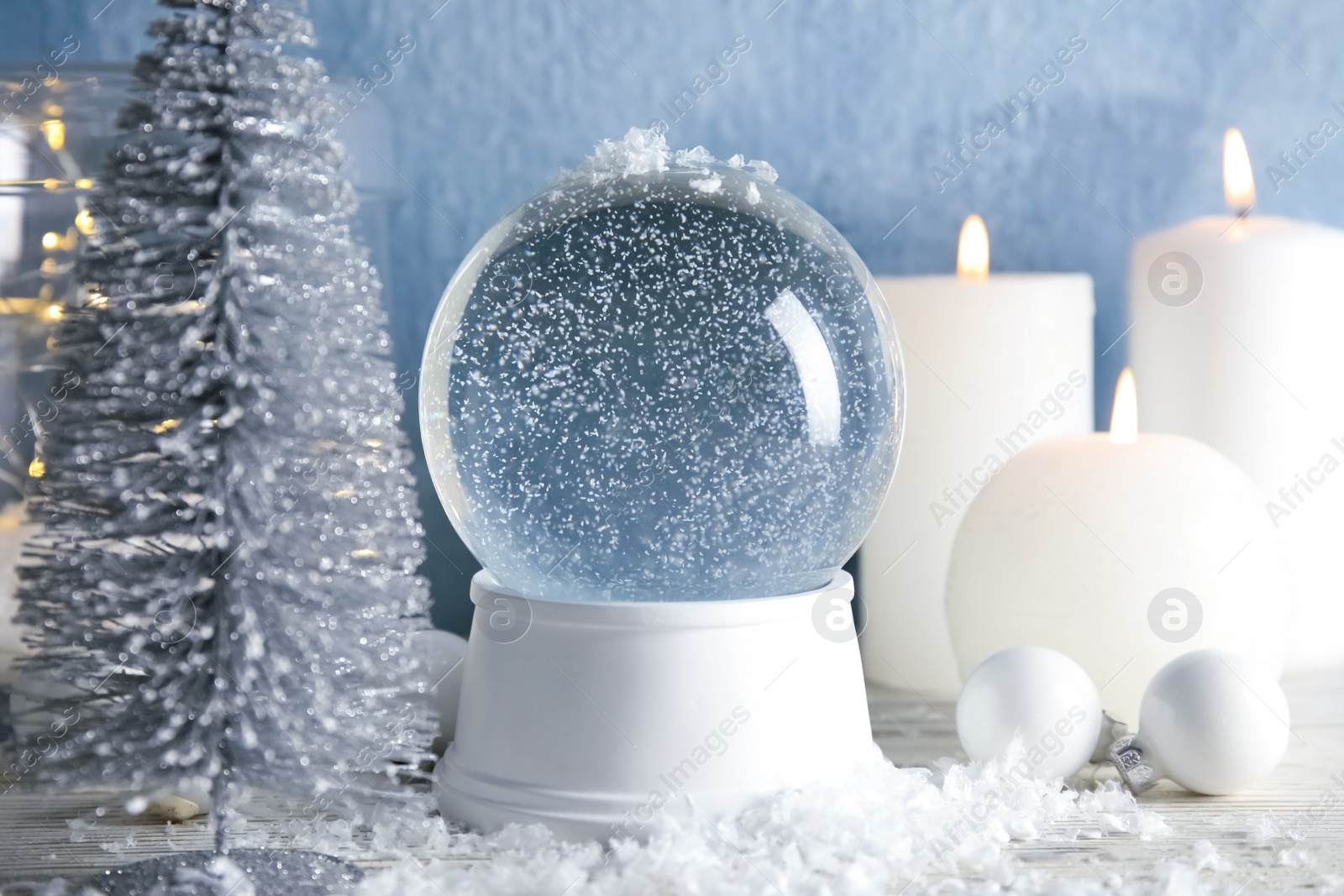 Photo of Magical empty snow globe with Christmas decorations and candles on table