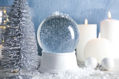 Magical empty snow globe with Christmas decorations and candles on table