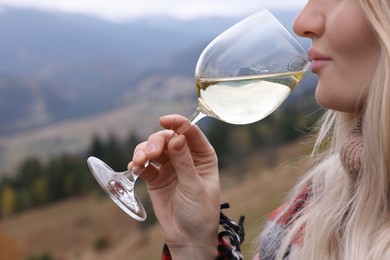 Photo of Young woman drinking wine in peaceful mountains, closeup