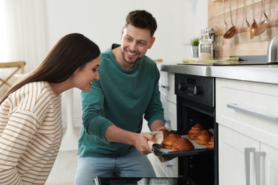 Couple baking buns in oven at home