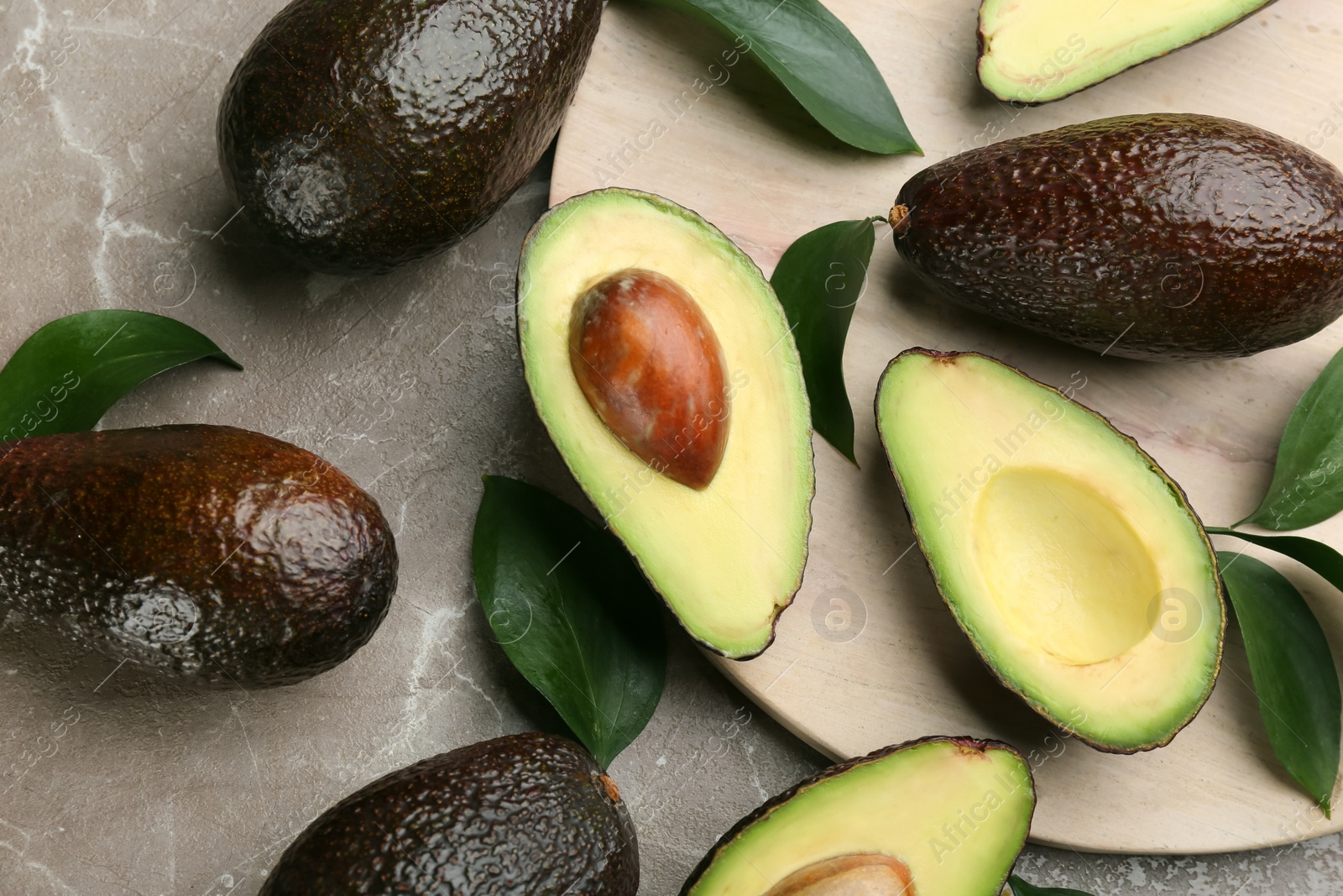 Photo of Whole and cut avocados on grey marble table, flat lay