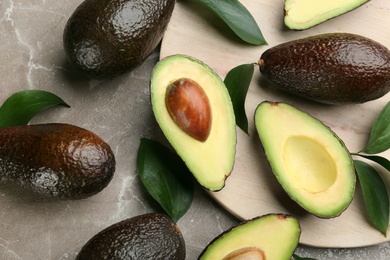 Photo of Whole and cut avocados on grey marble table, flat lay