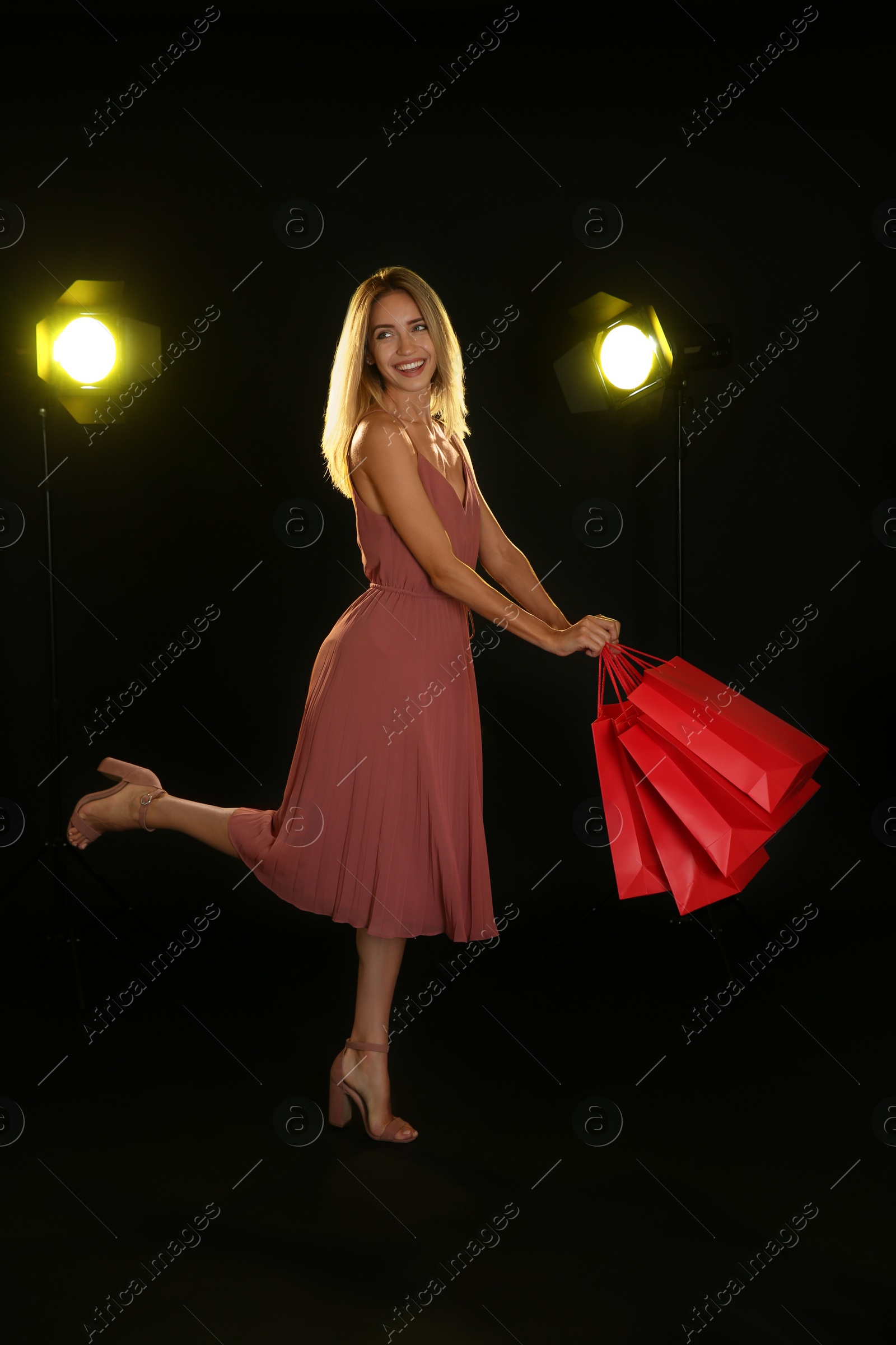 Photo of Happy young woman with shopping bags on dark background. Black Friday Sale