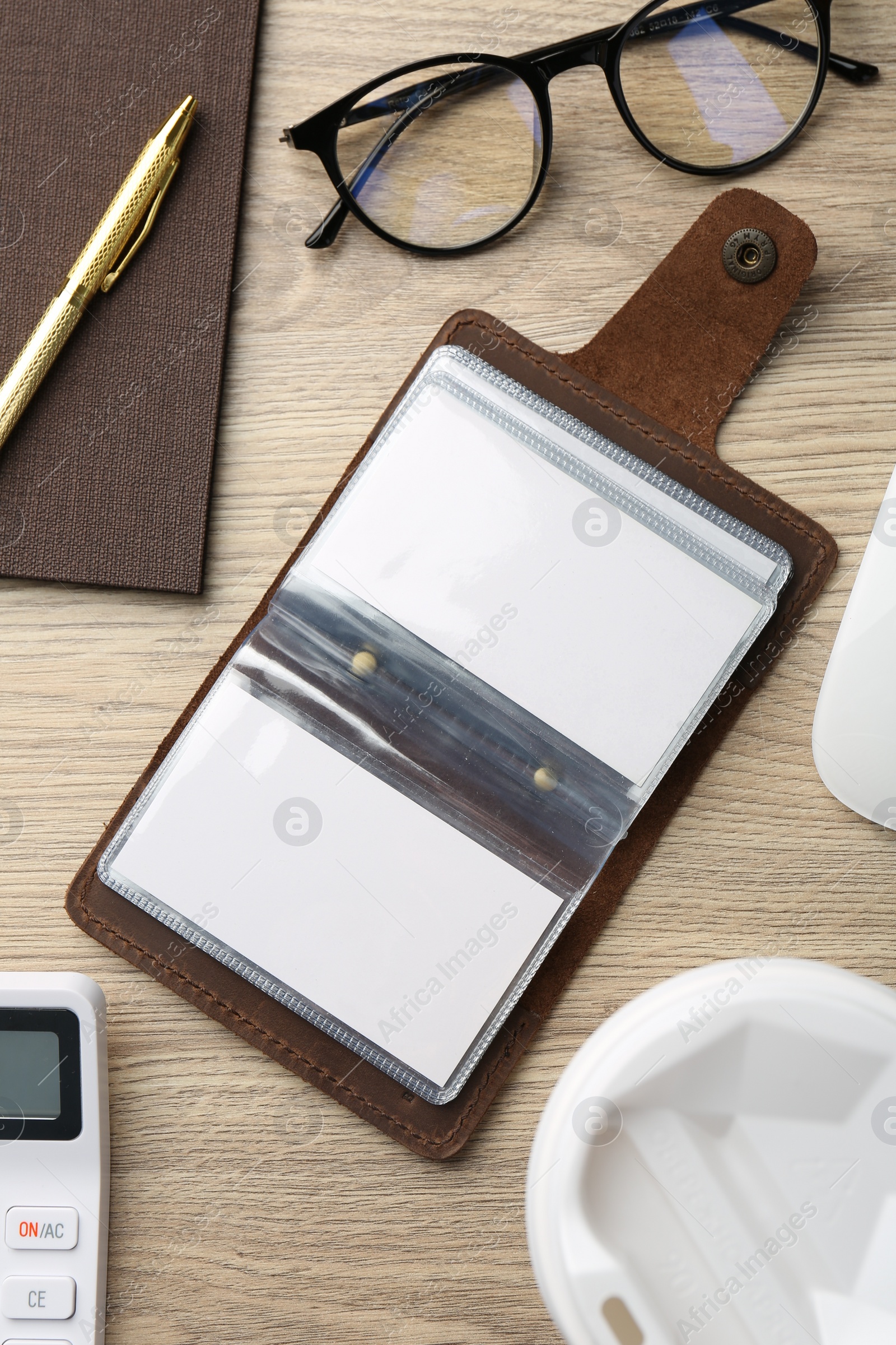 Photo of Leather business card holder with blank cards, stationery and glasses on wooden table, flat lay