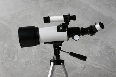 Tripod with modern telescope near grey wall, closeup