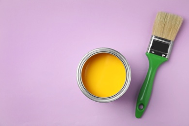 Photo of Open can with paint and brush on color background, top view. Space for text