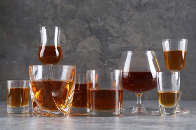 Many different liqueurs in glasses on grey textured table