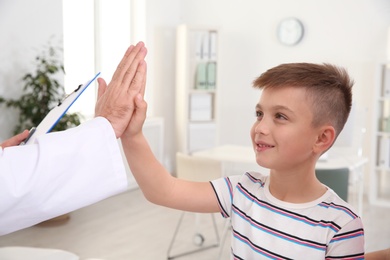 Photo of Children's doctor giving high five to patient in hospital