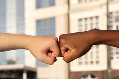 Photo of Men making fist bump on city street, closeup