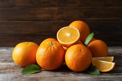 Photo of Fresh oranges with leaves on wooden table