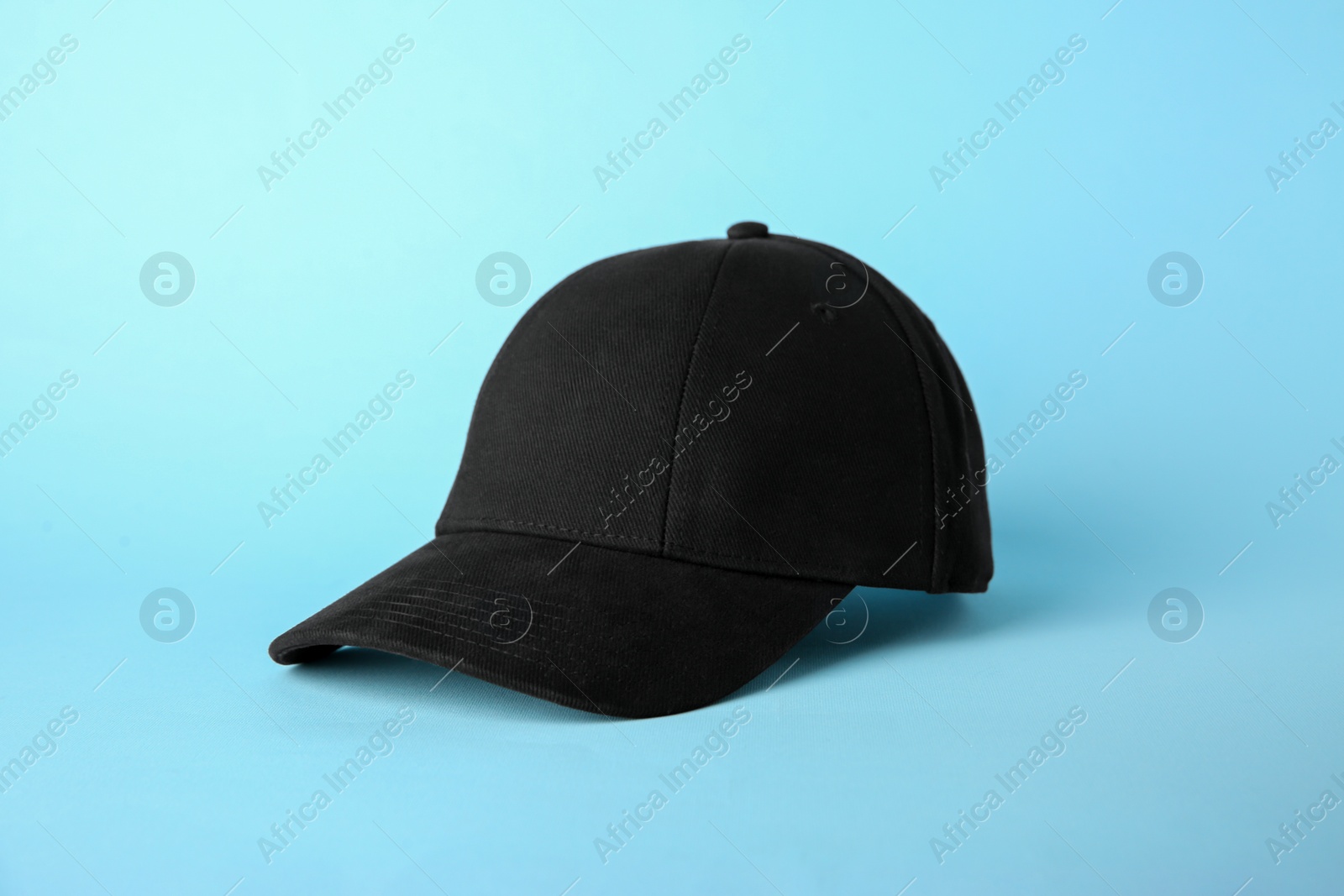 Photo of Stylish black baseball cap on light blue background