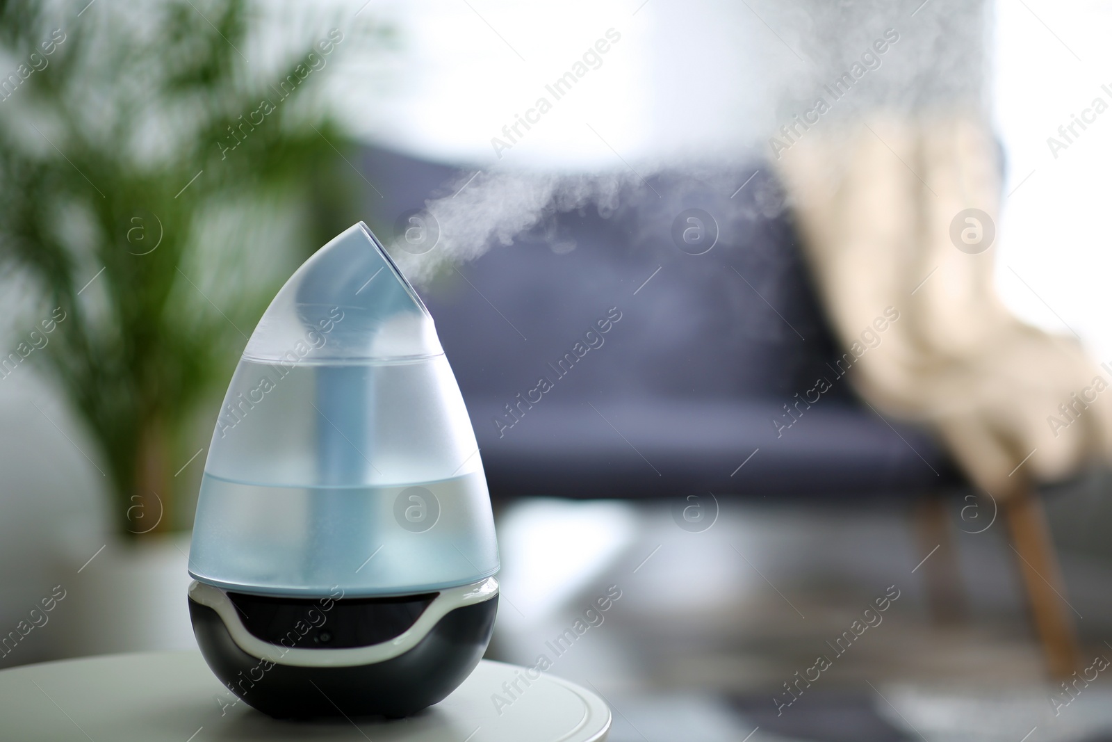 Photo of Modern air humidifier on table indoors. Space for text