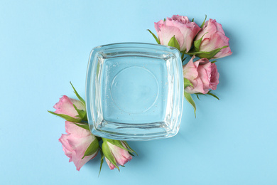 Flat lay composition with cosmetic gel and beautiful flowers on light blue background