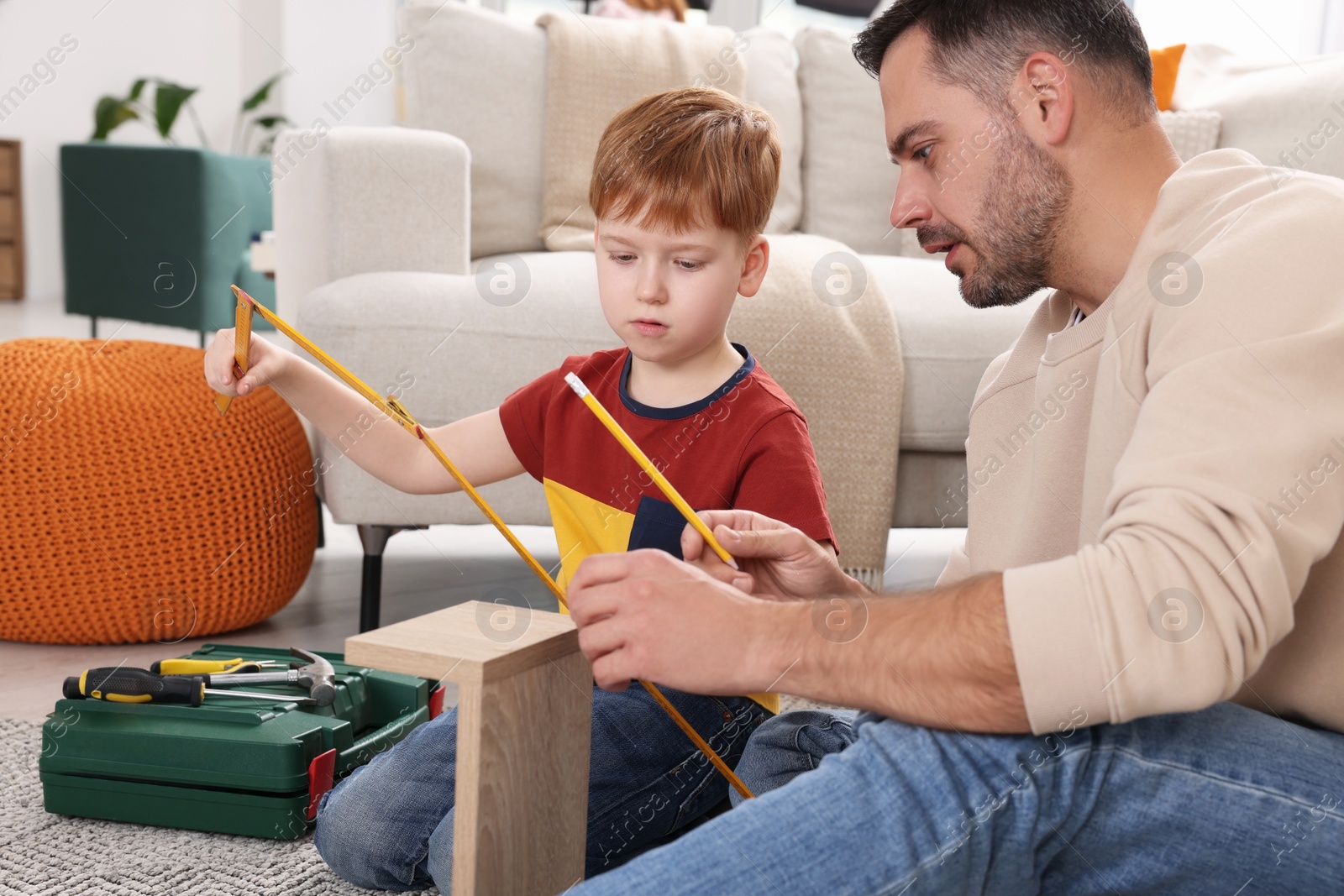 Photo of Father and son measuring shelf together at home. Repair work