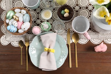 Photo of Festive table setting with painted eggs, flat lay. Easter celebration