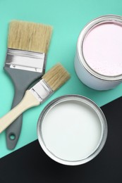 Cans of white paint and brushes on color background, flat lay