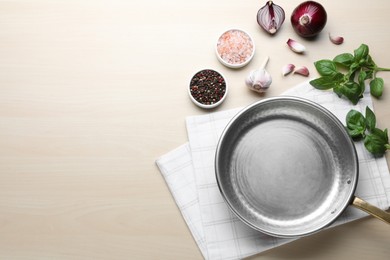 Photo of Empty frying pan, fresh vegetables, spices and basil on wooden table, flat lay. Space for text
