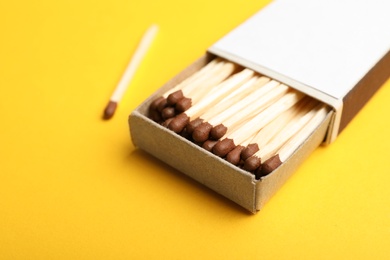 Photo of Cardboard box with matches on color background, closeup