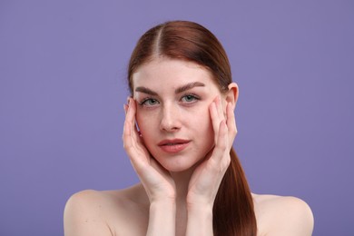 Portrait of beautiful woman with freckles on purple background