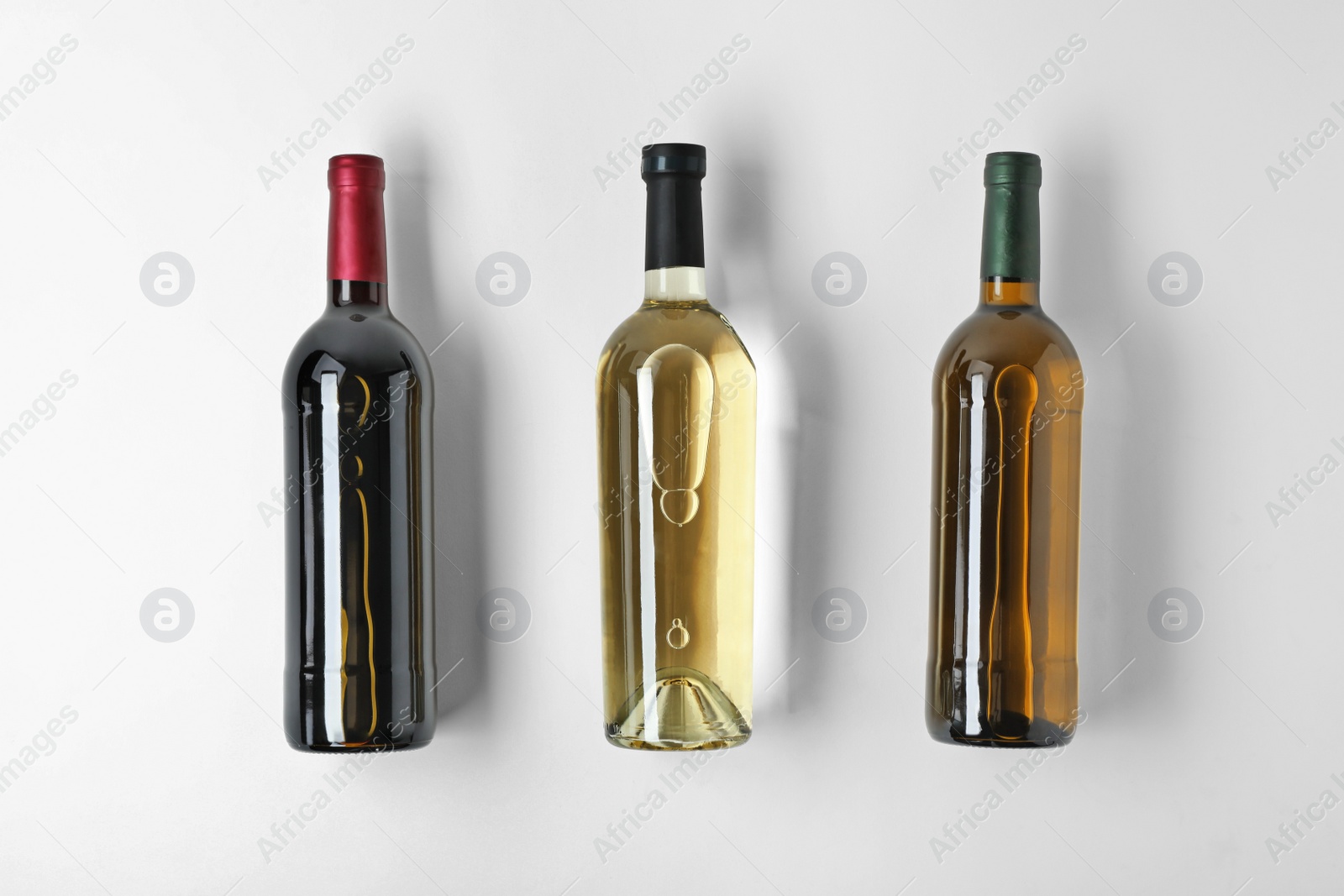Photo of Bottles with different types of wine on light background, top view
