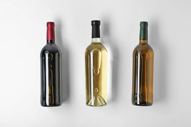 Bottles with different types of wine on light background, top view