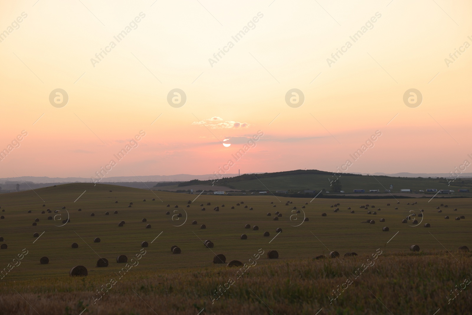 Photo of Beautiful view of agricultural field with hay bales at sunset