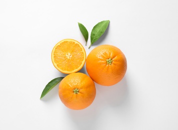 Photo of Juicy oranges and leaves on white background, top view