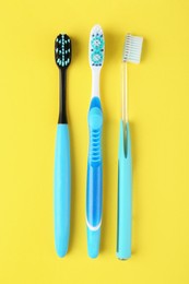 Different toothbrushes on yellow background, flat lay