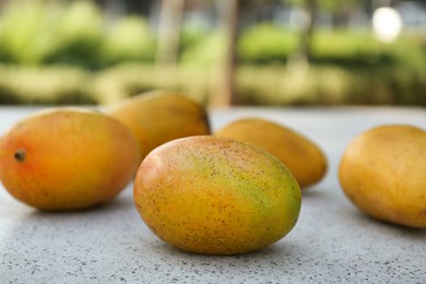 Photo of Delicious ripe juicy mangos on table outdoors, closeup