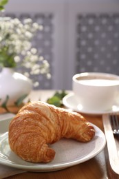 Photo of Tasty croissant served on wooden table indoors
