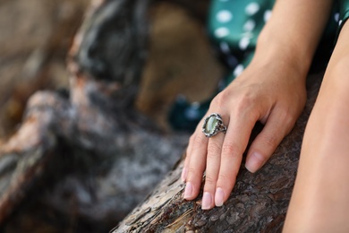 Photo of Young woman wearing beautiful silver ring with prehnite gemstone outdoors, closeup, Space for text