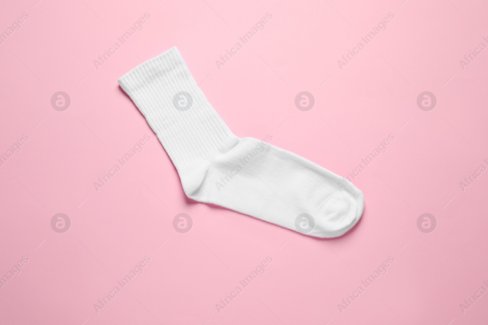 Photo of One white sock on pink background, top view