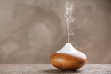 Photo of Aroma oil diffuser on table against grey background. Air freshener