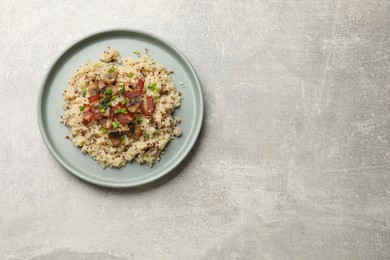 Photo of Plate of tasty quinoa porridge with fried bacon, mushrooms and green onion on light grey table, top view. Space for text