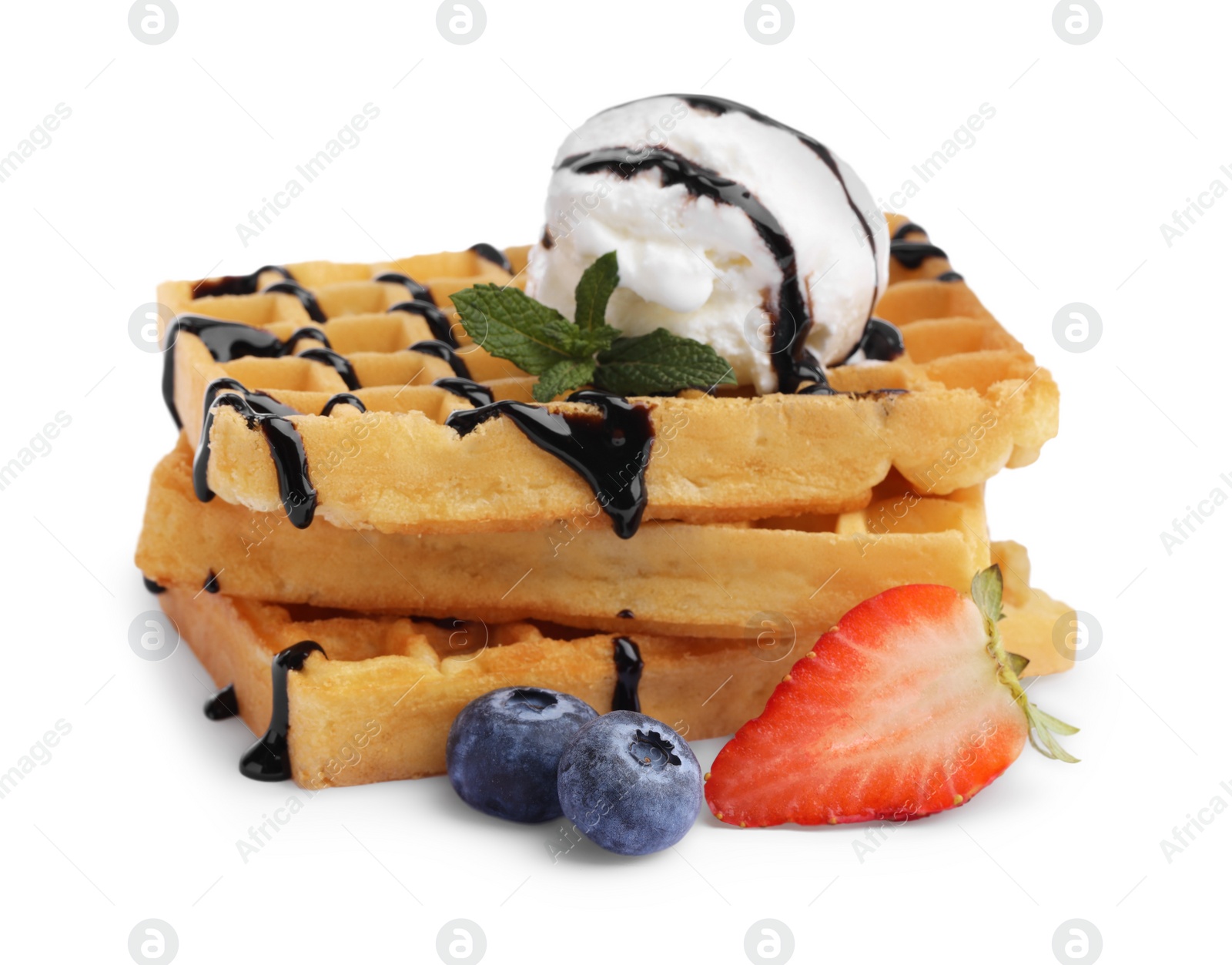 Photo of Tasty Belgian waffles with ice cream, berries and chocolate syrup on white background