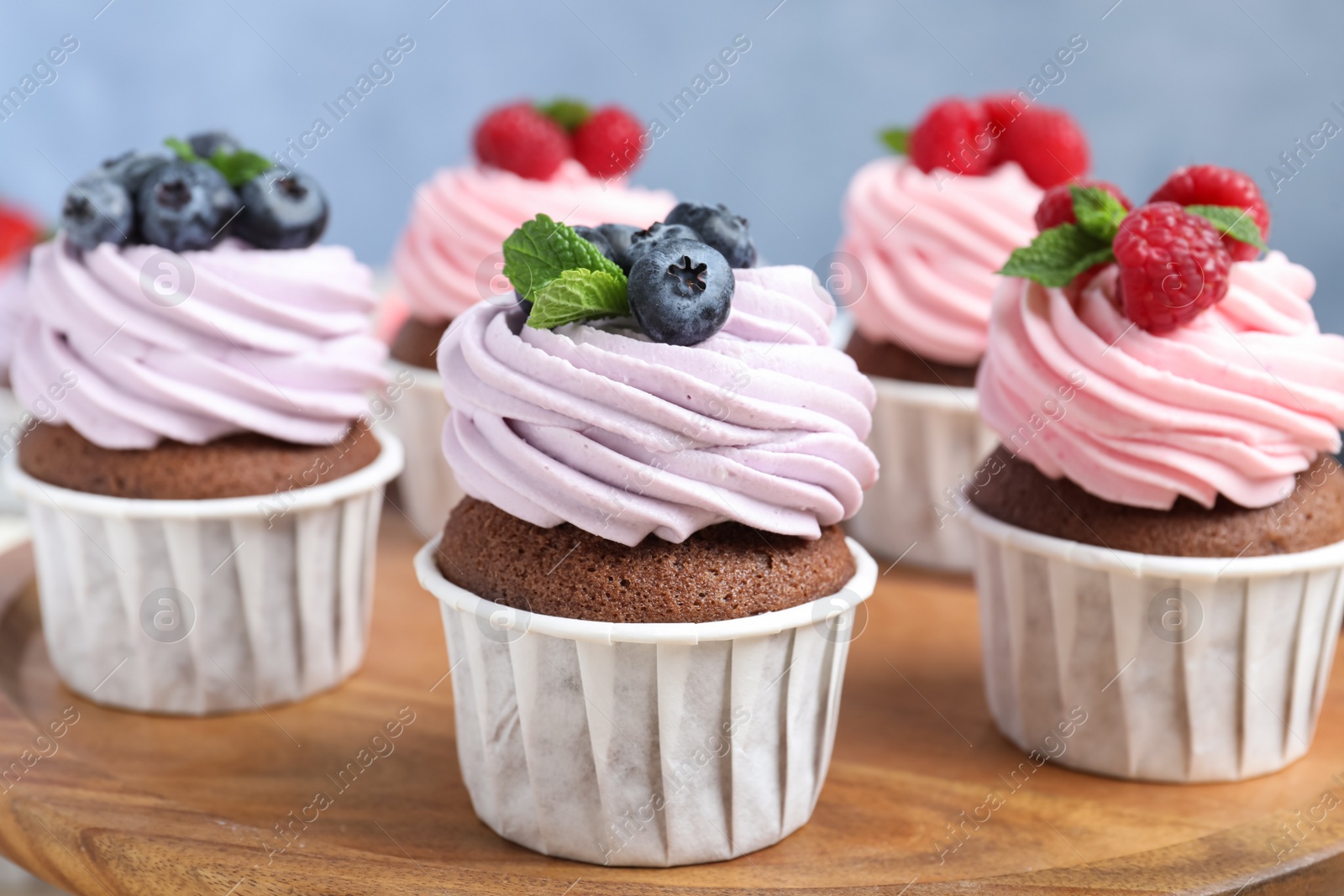 Photo of Sweet cupcakes with fresh berries on wooden board, closeup