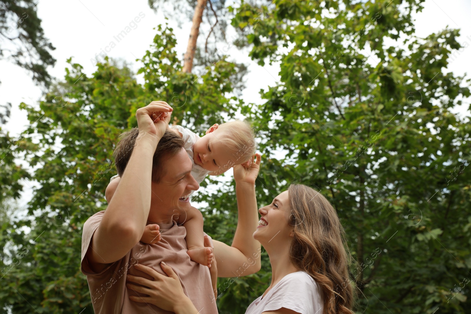 Photo of Parents with their cute baby spending time together outdoors. Happy family