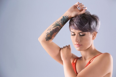 Photo of Young woman with tattoo on color background. Space for text