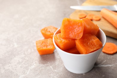 Photo of Bowl of frozen carrot puree cubes and ingredient on marble table, closeup. Space for text