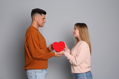 Photo of Man surprising his girlfriend with gift on grey background. Valentine's day celebration