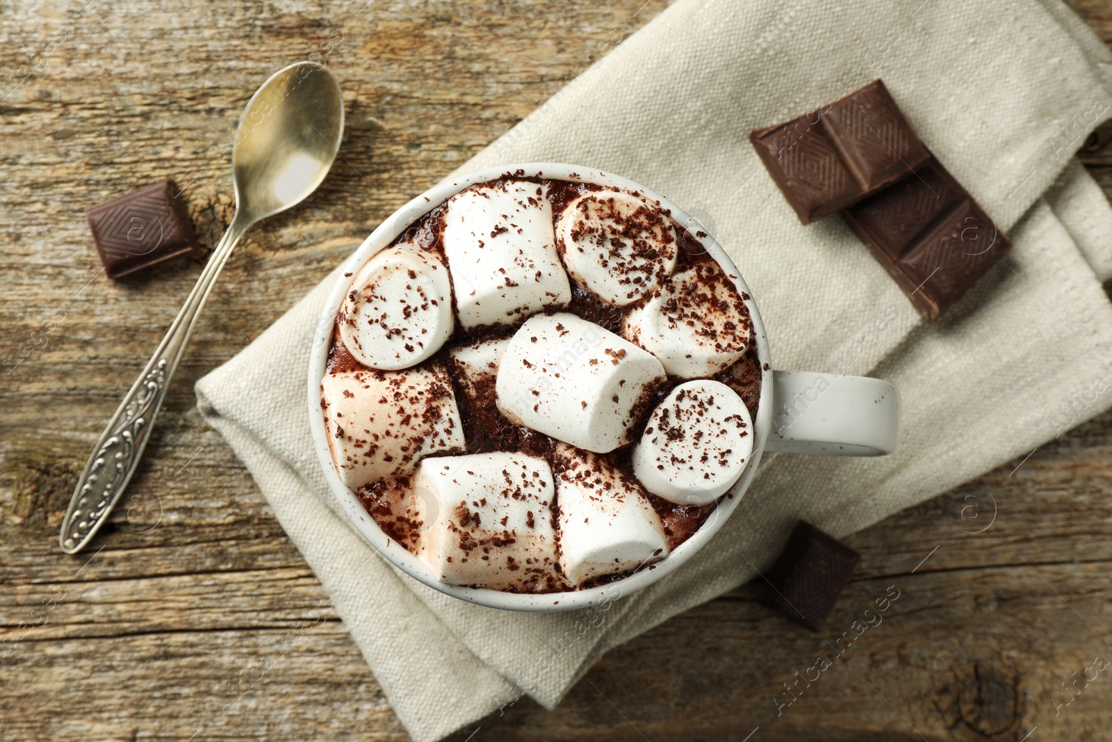 Photo of Delicious hot chocolate with marshmallows, cocoa powder and pieces on wooden table, flat lay