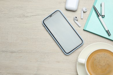 Notebook, smartphone and cup of coffee on wooden table, flat lay. Space for text