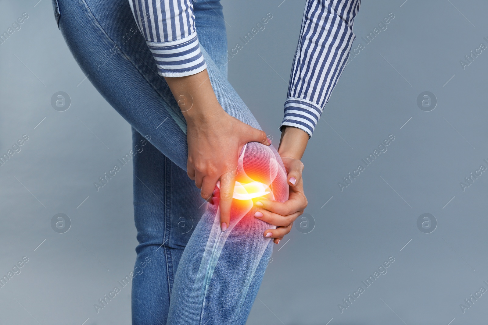 Image of Woman suffering from knee pain on grey background, closeup