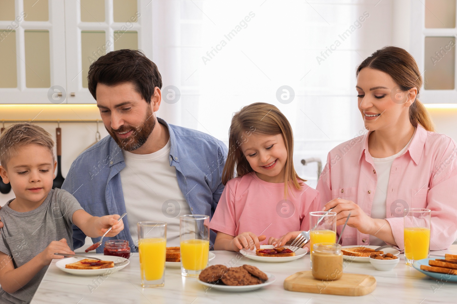 Photo of Happy family having breakfast at table in kitchen