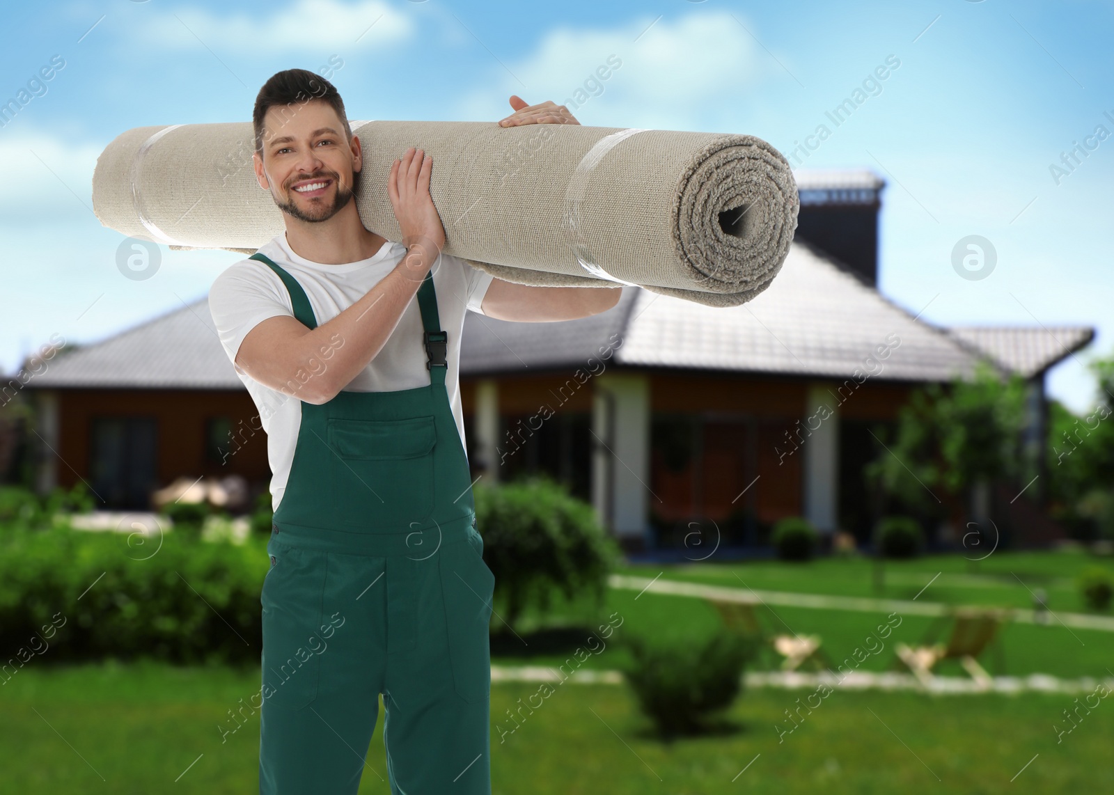 Image of Worker with rolled carpet outdoors on sunny day