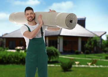 Image of Worker with rolled carpet outdoors on sunny day