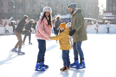 Happy family spending time together at outdoor ice skating rink