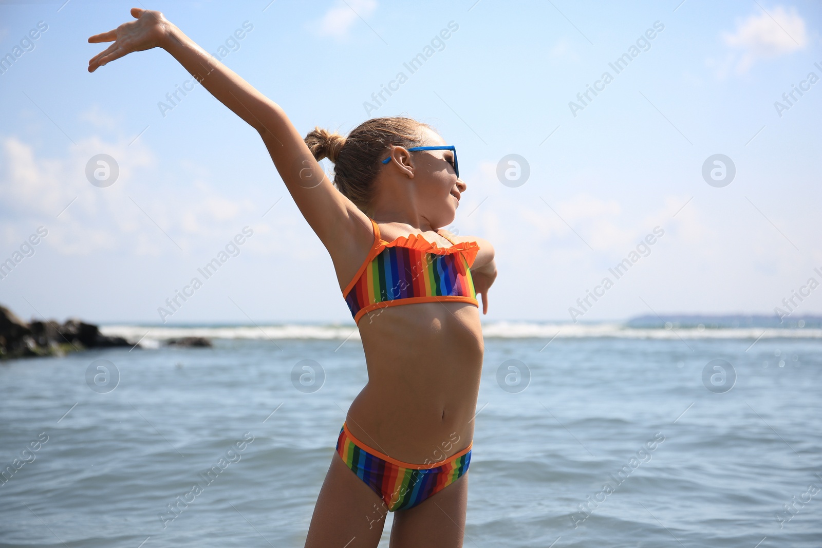 Photo of Little girl having fun in sea on sunny day. Beach holiday